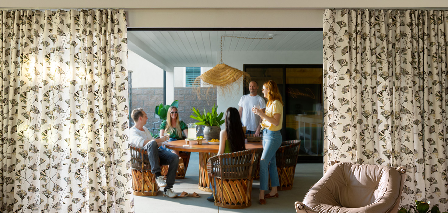 Drapes on a Large Open Sliding Glass door With Friends Gathered around a table.